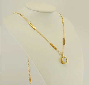Détail du collier asymétrique en or 18k avec pendentif en nacre sur buste blanc