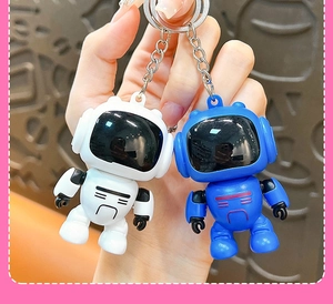Detailed macro view of cute white and blue cartoon astronaut robot keychains held in hand