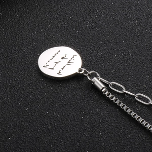 Macro detail of silver round pendant with elegant engraving and double style chain
