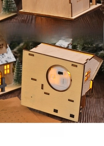 Detailed back view of a lit wooden Christmas house with a manual power switch and LED light