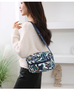 Detail of blue graffiti print crossbody bag with multiple zip pockets on model