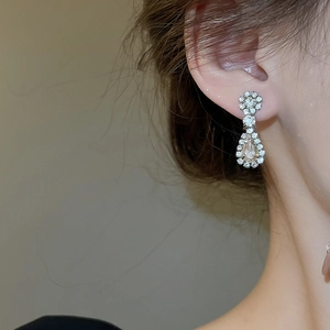 Close-up of sparkling silver floral drop earring with rhinestones on model's ear