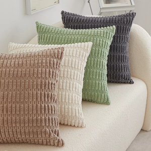 Set of four plush corduroy throw pillows in brown, beige, green, and grey on a sofa