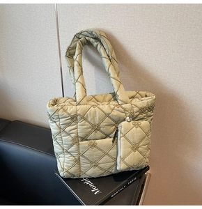 Close-up of quilted light green puffer tote bag with floral embroidery and mini pouch