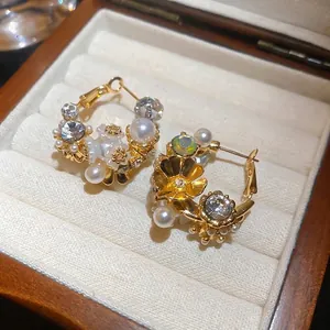 Elegant gold C-shaped hoop earrings with pearls and crystals in a velvet jewelry box