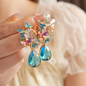 Detailed close-up of vintage butterfly drop earrings with blue crystal water droplets