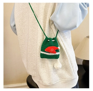Detail of green handmade crochet Christmas reindeer crossbody bag with red hat charm