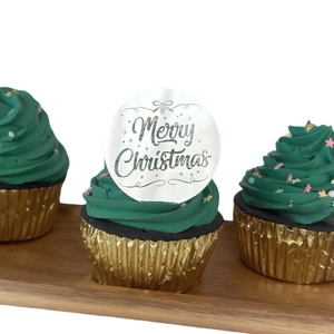 Close-up of silver mirror acrylic Merry Christmas cupcake toppers on green frosting