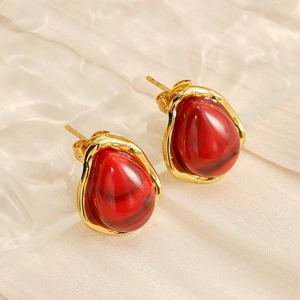 Close-up of red teardrop resin stud earrings with irregular gold vintage borders