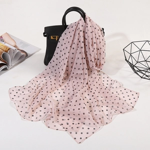 Lightweight pink chiffon scarf with black polka dots draped over a black handbag