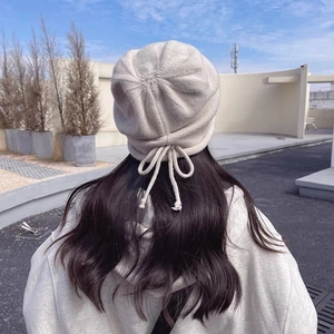 Oatmeal knitted beanie with a delicate bow drawstring on the back for women in winter
