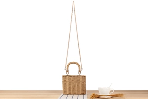 Detail of khaki woven box bag featuring gold chain strap and textured handle
