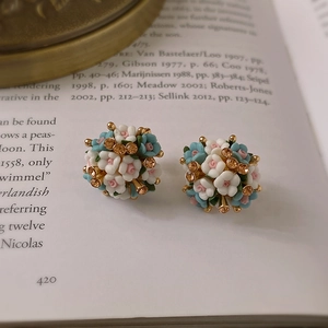 Detailed shot of floral cluster earrings with blue and white petals on a vintage book