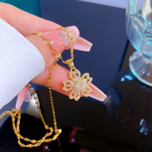 Gros plan du collier en titane doré avec un pendentif fleur étincelant en zircone