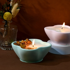 Blue and white petal shaped candle jars with dried flower decor and lit candle wicks