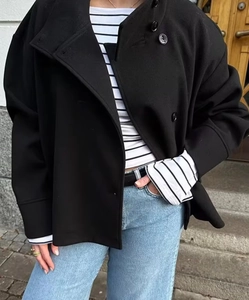 Detail der kurzen schwarzen Wolljacke mit Doppelreiher-Knöpfen und Streifenshirt