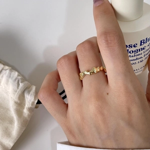 Detailed close-up of wavy irregular gold ring on finger with elegant aesthetic backdrop
