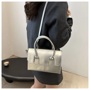 Silver metallic rectangular crossbody bag styled with a gray sweater and black skirt