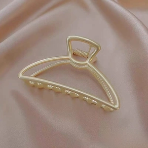 Detailed close-up of a 7.5cm gold hollow shark hair claw clip on champagne silk fabric