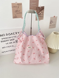 Close-up of pink checkered tote bag with red bows and light green woven handles