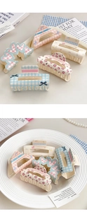 Flat lay of assorted acrylic hair claws with floral, plaid, and bow patterns on a desk