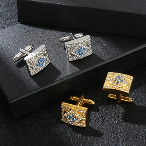 Detailed view of silver and gold rectangular cufflinks with blue and white crystals