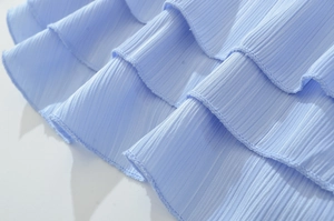 Détail d'une robe bleu clair avec des volants plissés et de fines rayures verticales