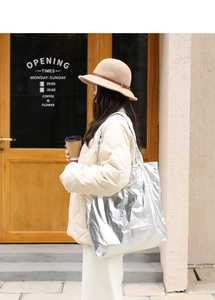 Silver metallic nylon tote bag styled with a beige jacket in a street fashion shot