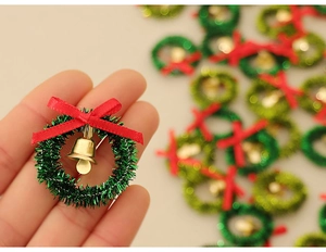 Close-up of a mini green Christmas wreath with a red bow and a gold bell accessory