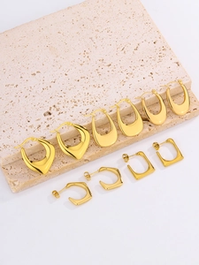 Polished 18K gold-plated oval hoop earrings arranged on a natural stone surface