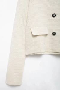 Détail du cardigan en maille écrue avec texture et boutons foncés contrastés