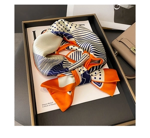 Close-up of geometric silk scarf with polka dots and stripes tied in a bow on a tray