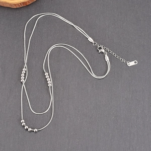 Double-layered silver snake chain necklace with metallic beads and K18 hallmark detail