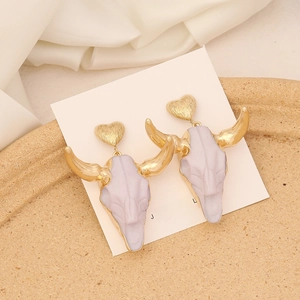 Detail of bohemian bull skull earrings with gold hearts on a white display card