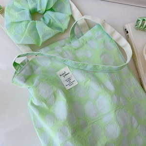 Close-up of mint green pleated cotton tote bag with circular print and matching scrunchie