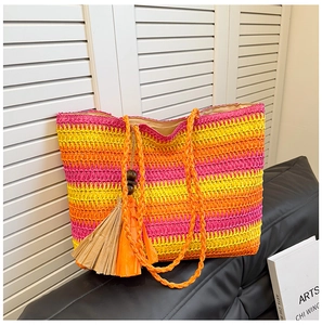 Detail of colorful striped straw tote bag featuring decorative fringe and wooden beads