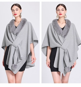 Detail of grey faux fur collar and pom-poms on a knitted poncho cardigan cape