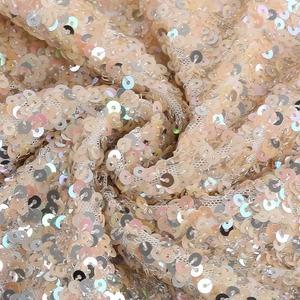 Macro shot of shimmering champagne sequins on soft mesh fabric for evening dresses