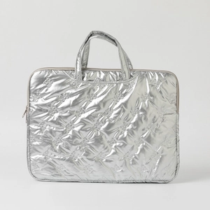 Close-up of metallic silver quilted laptop sleeve with floral stitching and sturdy handles