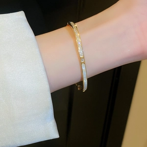 Dettaglio del bracciale placcato in oro con zirconi e intarsio in conchiglia sul polso