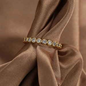 Minimalist gold plated brass ring with white zircon stones on brown silk background