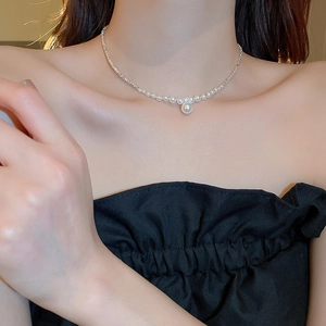 Detail view of a silver necklace featuring gradient beads and a central pearl on a model