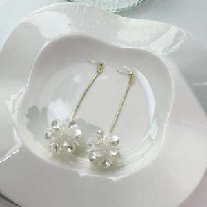 Detailed macro view of white shell flower earrings with long gold tassel chains