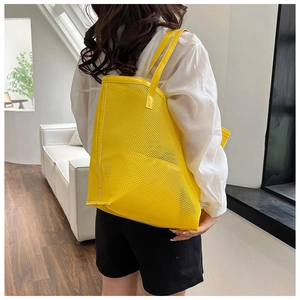 Bright yellow mesh beach bag styled as a large shoulder tote shown on a model