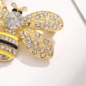 Golden bee brooch with sparkling rhinestones and black enamel stripes on white background