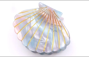Macro detail of shell hair claw clip with pearlescent finish and gold etched lines