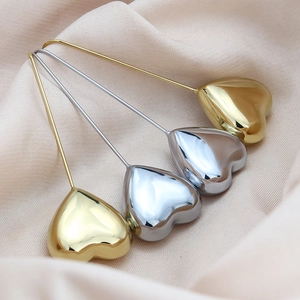 Elegant gold and silver heart-shaped drop earrings displayed on soft silk fabric