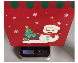 Weight measurement of a festive red snowman gift box on a digital kitchen scale