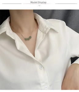 Close-up of elegant gold chain necklace with three round green jade beads on a model