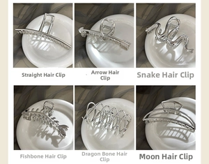 Detail view of six silver metal hair claws including snake, fishbone, and moon shapes